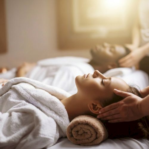 A person receiving a relaxing head and neck massage in a calm spa setting, with towels and soft lighting.