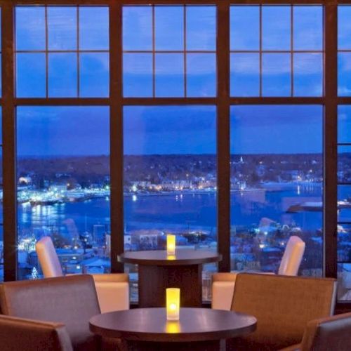 A cozy lounge with warm seating, candles on small tables, and a panoramic city view through tall windows at dusk. End.